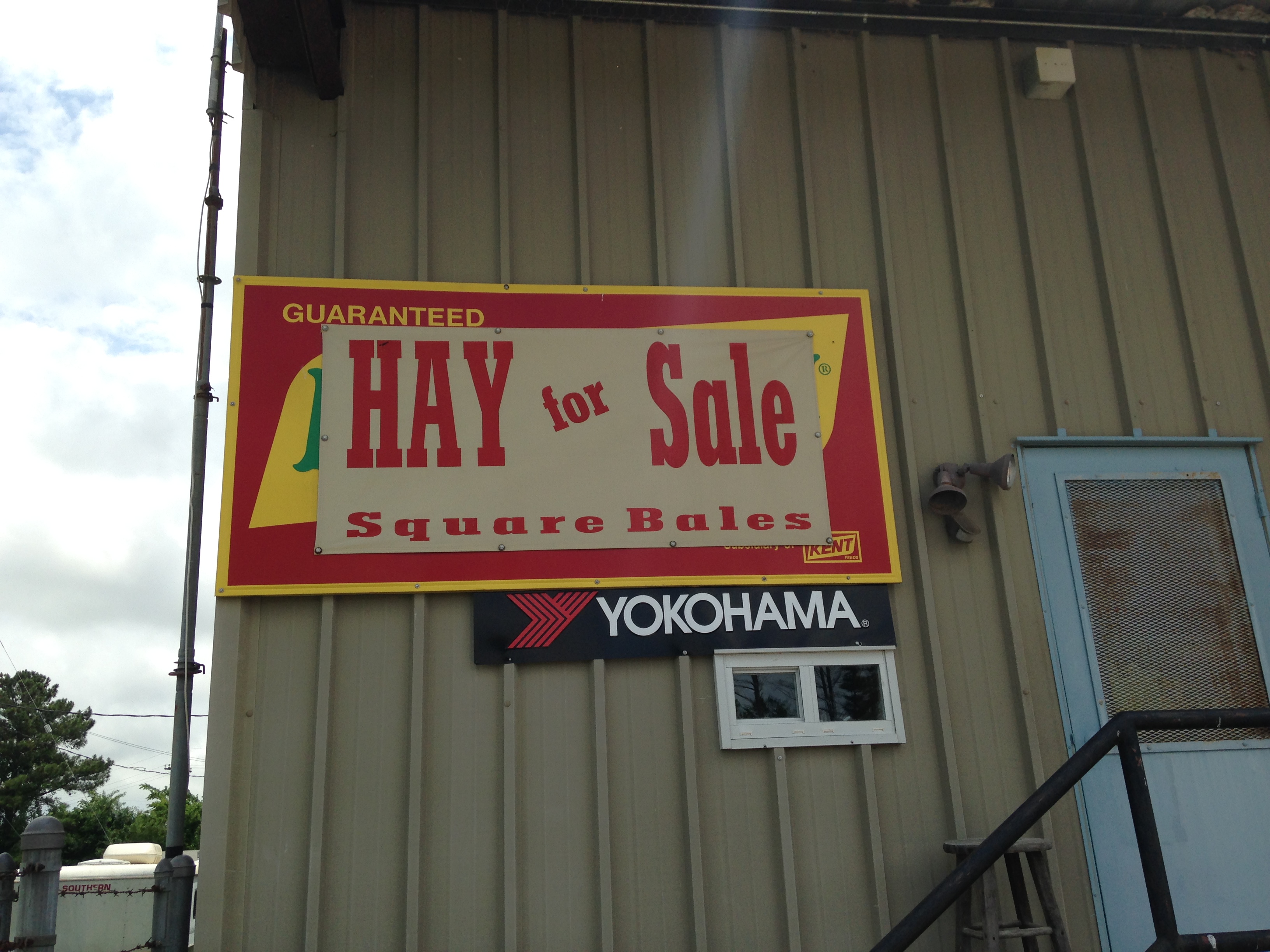 Hay for sale sign for square bales posted on the side of our building